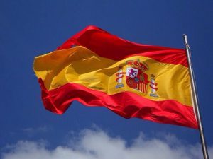 Flagge Spaniens im Wind vor blauem Himmel