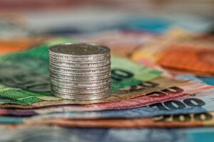 Euromünzen aufgetürmt, stehen auf mehreren Euroscheinen